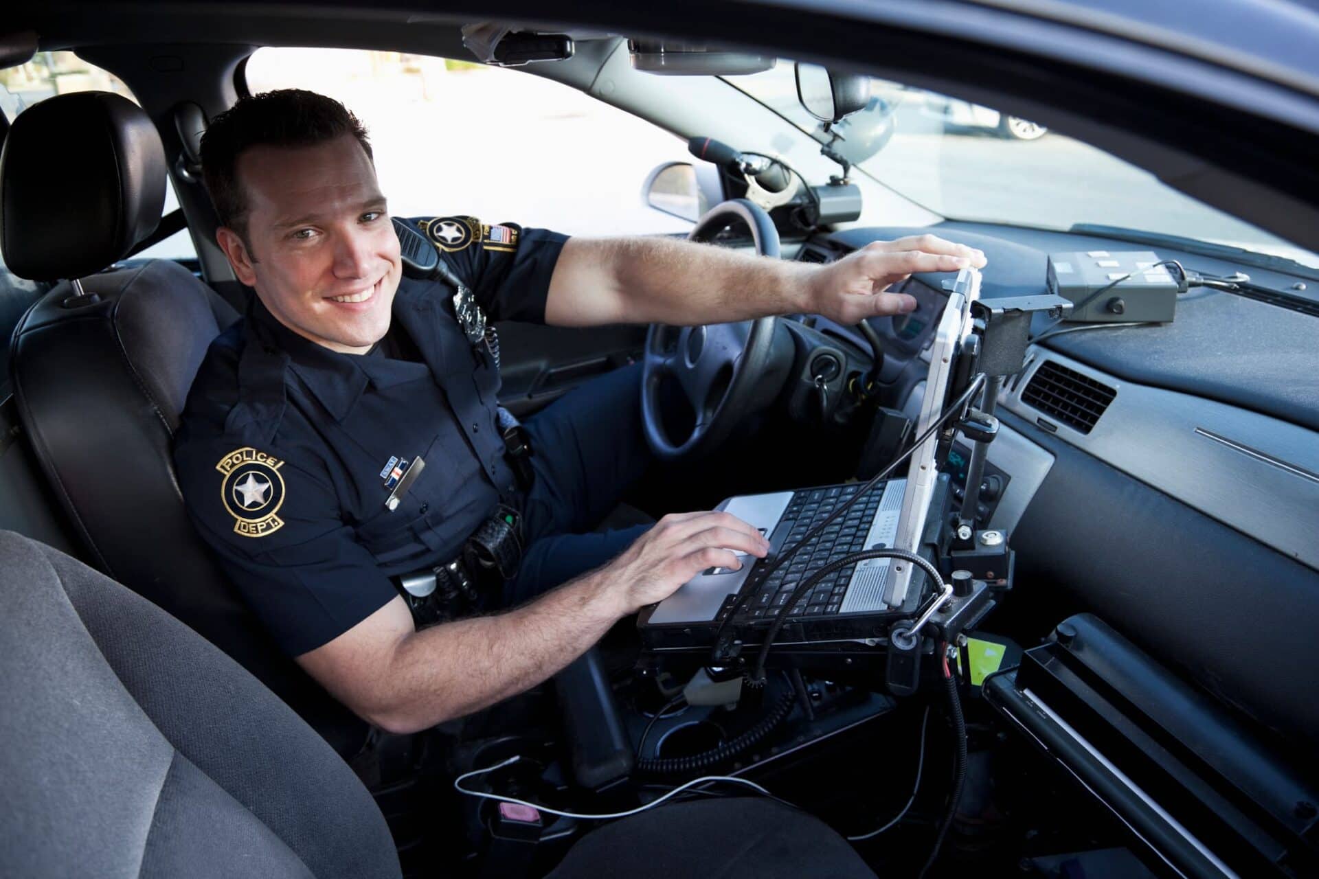 male policeman using his laptop computer inside his police vehicle