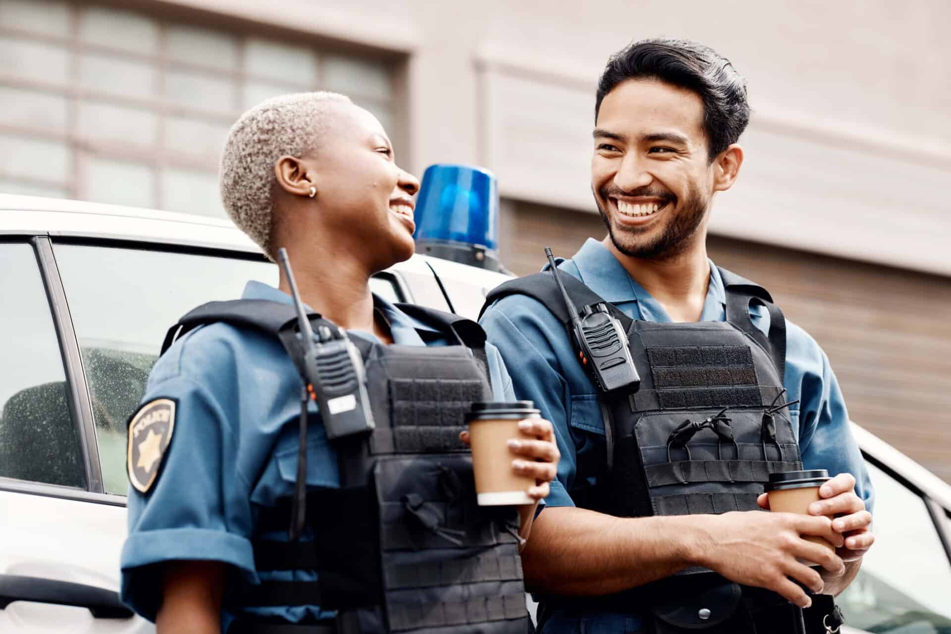 male and female police officers smiling with coffee in their hands